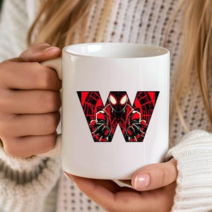 Może przedstawiać: Biały kubek ceramiczny z czerwoną i czarną grafiką postaci superbohatera tworzącego literę "W".
