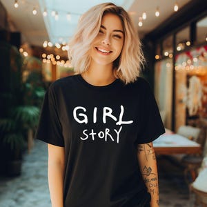 K&ouml;nnte beinhalten: Ein schwarzes T-Shirt mit dem Aufdruck "GIRL STORY" in wei&szlig; auf der Vorderseite.