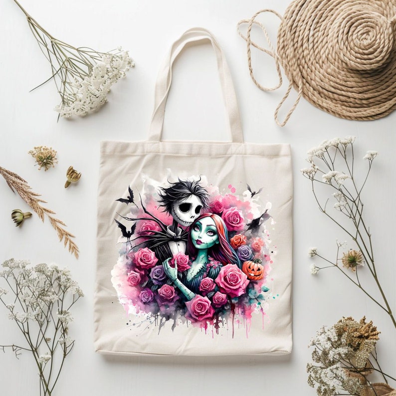 Może przedstawiać: Biała torba z pł&oacute;tna z kolorową ilustracją Jacka Skellingtona i Sally z filmu Koszmar przed świętami. Ilustracja zawiera r&oacute;żowe r&oacute;że, nietoperze i dynię.