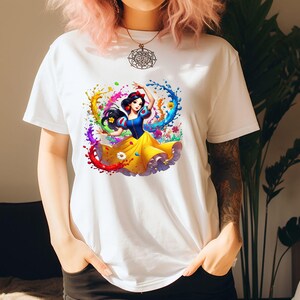 Op de afbeelding: Wit T-shirt met een kleurrijke afbeelding van Sneeuwwitje die danst in een wervelwind van verf.
