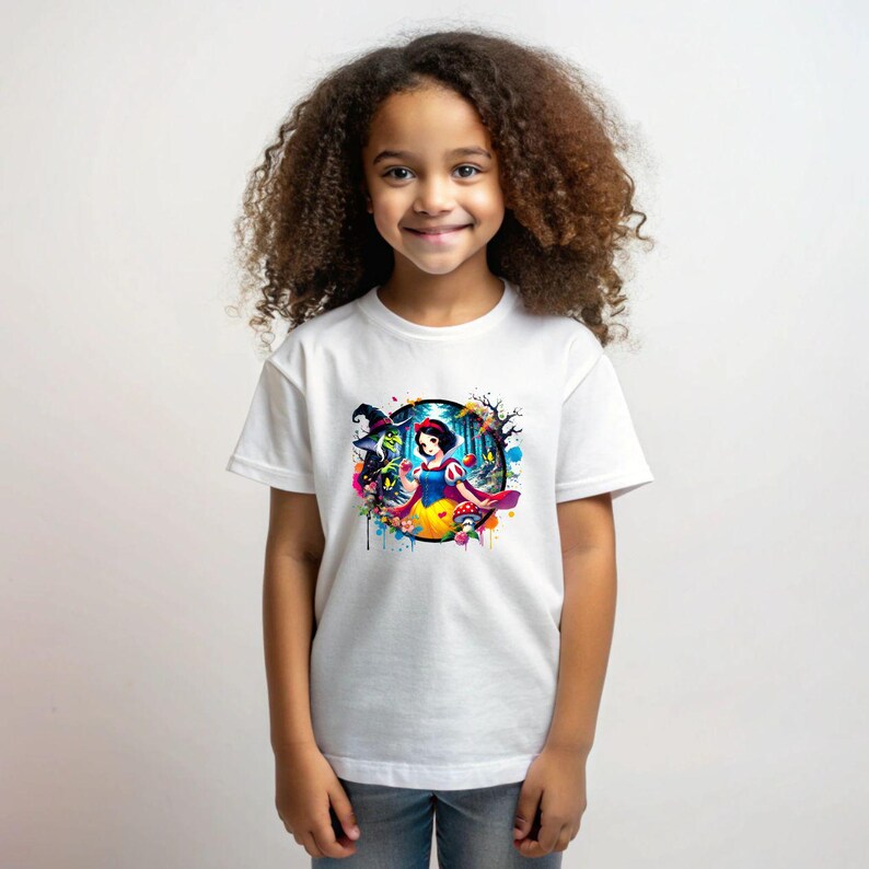 Op de afbeelding: Een wit T-shirt met een kleurrijke grafische print van Sneeuwwitje en de boze Koningin uit de Disney-film Sneeuwwitje en de zeven dwergen. De afbeelding is omringd door een cirkel van kleurrijke verfspatten.