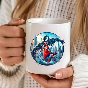 May include: White ceramic mug featuring a colourful illustration of Spider-Man and Venom battling in a city skyline. The mug has a black handle.