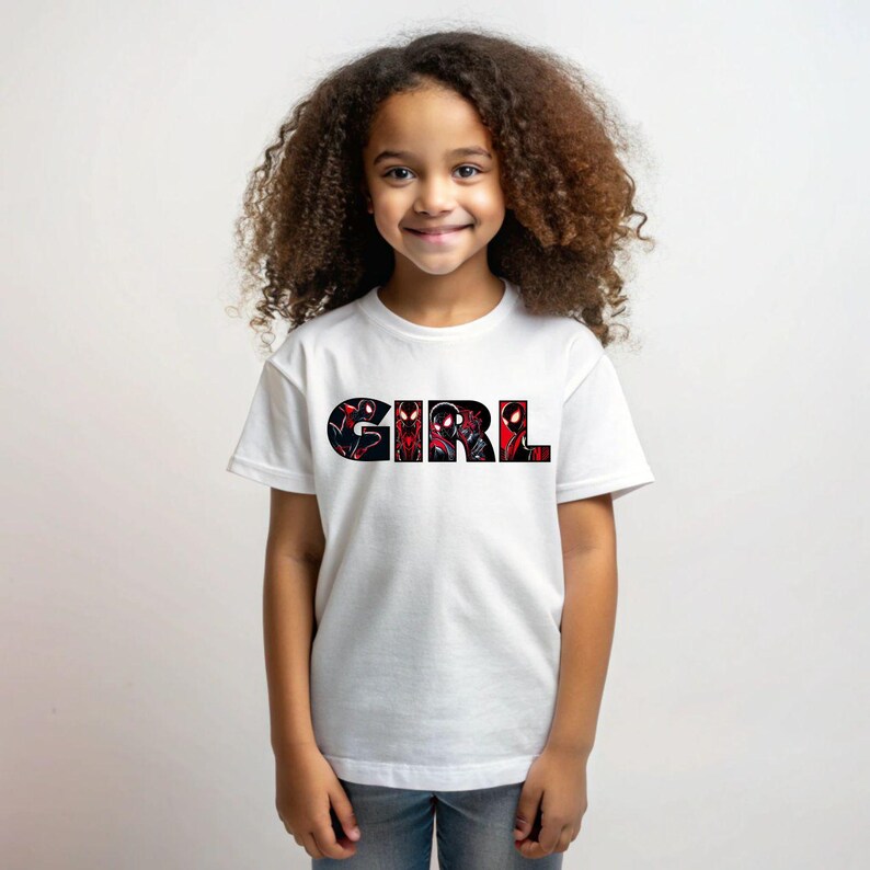 Może przedstawiać: Biała koszulka z nadrukiem graficznym słowa "GIRL" czarnymi literami. Litery są wypełnione czerwono-czarną grafiką superbohatera.