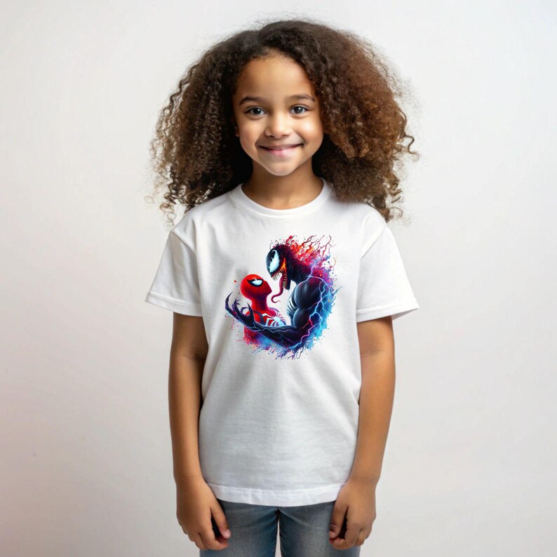 May include: A white t-shirt featuring a colourful graphic print of Venom and Spider-Man. The graphic depicts Venom with his mouth open and Spider-Man in his arms. The graphic is surrounded by a blue and red watercolour effect.