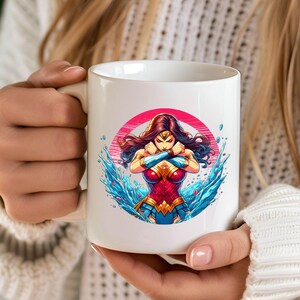 May include: White ceramic mug with a colorful illustration of Wonder Woman standing in water. The illustration is surrounded by a pink circle.