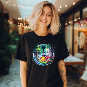 Op de afbeelding: Een zwart T-shirt met een kleurrijke grafische print van Sneeuwwitje en een wolf in een bossetting. De grafiek gebruikt een blauw, groen en paars kleurenschema.