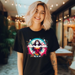 May include: Black t-shirt featuring a colorful graphic of Wonder Woman. The design includes a portrait of the superheroine within a blue and pink circular splash. The shirt is a classic crew neck style.