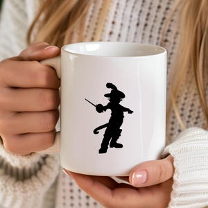 Pu&ograve; includere: Una tazza in ceramica bianca con una silhouette nera di un gatto che indossa un cappello e tiene una spada. Il gatto &egrave; in piedi sulle zampe posteriori e ha una lunga coda.