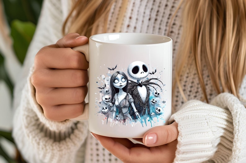 Może przedstawiać: Biały kubek ceramiczny z akwarelowym wzorem Jacka Skellingtona i Sally z filmu Koszmar przed świętami. Wz&oacute;r zawiera niebieskie i białe plamy akwarelowe oraz czaszki.