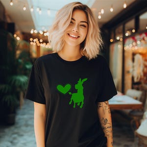 Pu&ograve; includere: Una maglietta nera con una silhouette verde di un asino con un cuore di fronte. L'asino indossa un cappello e ha una coda.