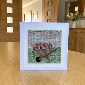Sewn fabric, wheelbarrow of flowers.   Block print foliage, appliqué and  free motion embroidery handmade  textile greetings card.