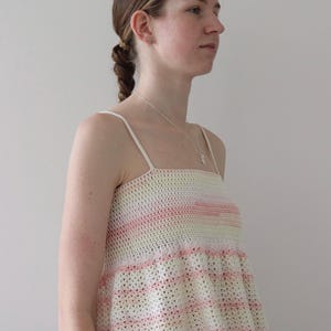 Puede incluir: Un top de crochet a rayas de color rosa pastel, blanco y amarillo con un dobladillo con volantes.