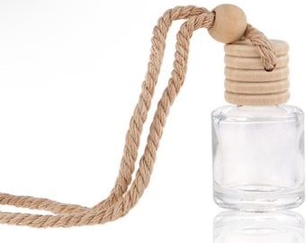 May include: A clear glass bottle with a wooden cap and a natural rope cord. The bottle is rectangular with rounded corners. The wooden cap has a layered design and a small wooden bead at the top. The rope is a light brown color.