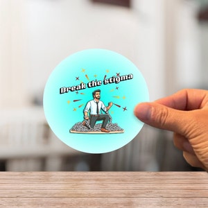 May include: A round sticker featuring the text "Break the stigma" and an illustration of a man breaking chains. The man is dressed in a white shirt, black tie, and grey trousers. The background is light blue with starbursts.
