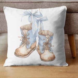 May include: Watercolor illustration of two baby boots hanging from blue ribbons. The boots are light blue with brown accents and laces. The background is white, and the boots appear to be suspended in the air. The overall theme is baby or nursery decor.