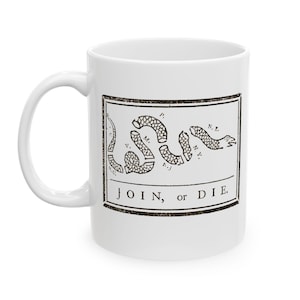 May include: White ceramic mug featuring a black and white illustration of a segmented snake with the words "JOIN, or DIE." The design is a historical symbol, printed within a rectangular frame. The mug has a curved handle.