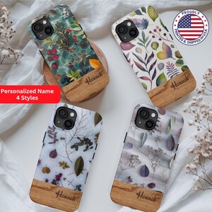 May include: Four different iPhone cases with a wood accent and a floral design. The cases feature a variety of floral patterns, including leaves, flowers, and berries. The wood accent is a light brown color and has the name "Hannah" engraved on it. The cases are all printed and shipped in the USA.