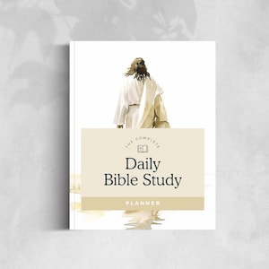 Könnte beinhalten: Ein weißer Daily Bible Study Planer mit einer Illustration einer Figur in weißen Gewändern. Der Planer trägt den Text "The Complete Daily Bible Study Planner" in einem beigen Rechteck.