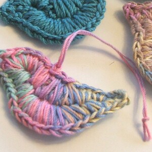 Puede incluir: Tres formas de medio c&iacute;rculo de ganchillo en rosa, azul y beige. La forma rosa y beige est&aacute; en primer plano y tiene un degradado de color azul claro y rosa.