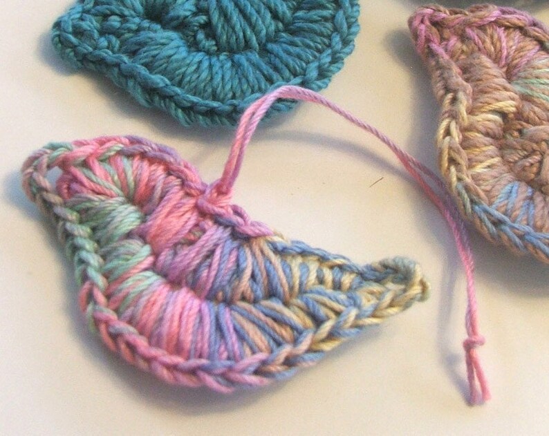 Puede incluir: Tres formas de medio c&iacute;rculo de ganchillo en rosa, azul y beige. La forma rosa y beige est&aacute; en primer plano y tiene un degradado de color azul claro y rosa.