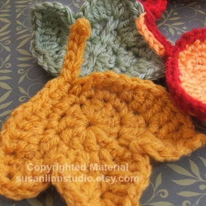 Peut inclure: Des formes de feuilles en crochet dans des tons de vert, orange et rouge. Les feuilles sont disposées en grappe et sont réalisées avec un point texturé. Le texte "Copyrighted Material susanlimstudio.etsy.com" est visible dans le coin inférieur droit de l'image.