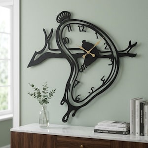Könnte beinhalten: Eine schwarze Wanduhr in Form einer schmelzenden Taschenuhr, die über einem horizontalen Ast hängt. Die Uhr hat goldfarbene Stunden- und Minutenzeiger sowie schwarze Ziffern von eins bis zwölf, die in den Rahmen integriert sind.