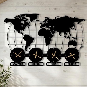 May include: A black metal world map wall clock with four round clocks below. The clocks display the time for New York, London, Rome, and Custom. The clock hands are gold. The background is a white wooden wall.