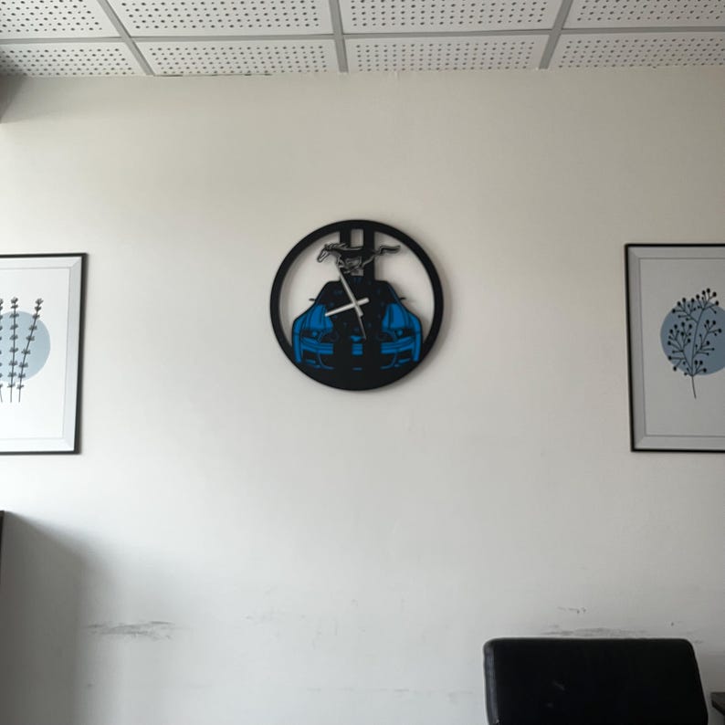 May include: A black wall clock featuring a blue sports car design. The clock has a circular shape with a car silhouette and a horse emblem. The clock hands are white, and the clock is mounted on a white wall.