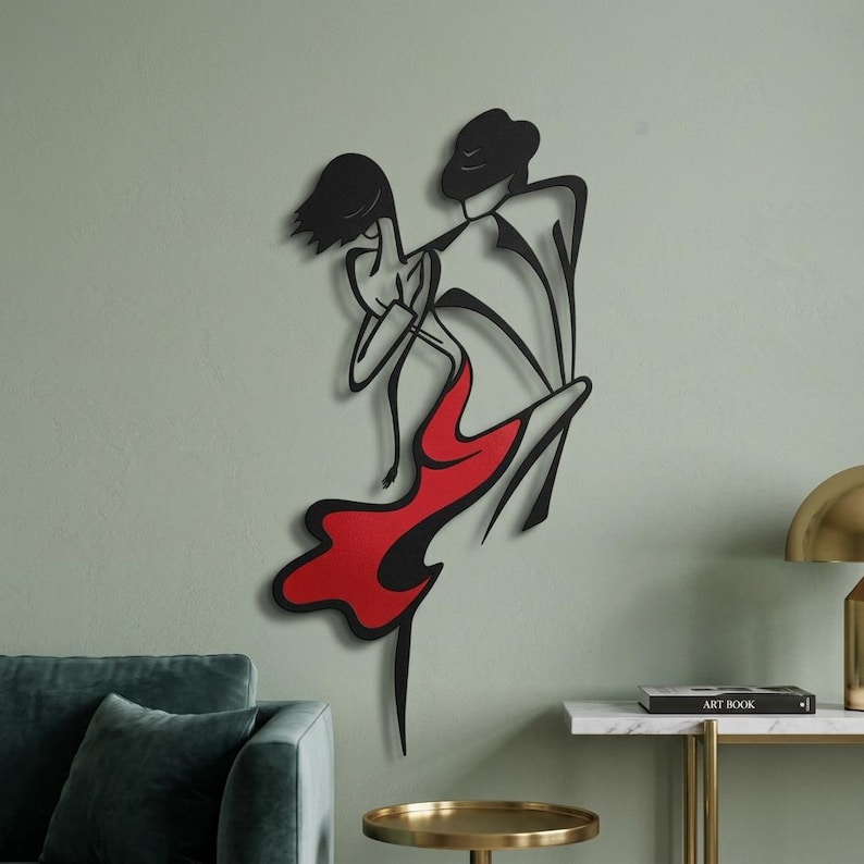 May include: A black metal wall art piece depicting two figures in a dance pose. The male figure is outlined in black, while the female figure features a solid red dress section. The design uses clean, continuous lines to form the silhouettes.