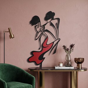 May include: A black and red metal wall art piece depicting a stylized silhouette of two figures dancing. The design features fluid, minimalist lines with the female figure wearing a flowing red dress and the male figure in a dark suit.