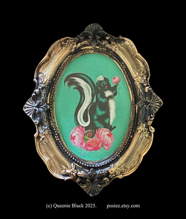 May include: A framed illustration of a black and white skunk holding a pink flower. The skunk is surrounded by pink flowers and green foliage. The frame is gold with black accents.