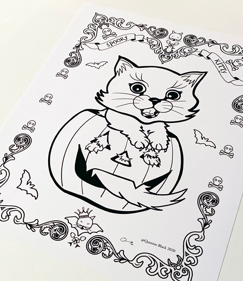 Pode incluir: Um desenho em preto e branco de um gato sentado dentro de uma ab&oacute;bora de Halloween. O gato est&aacute; usando uma coroa e tem uma express&atilde;o assustadora. A imagem &eacute; cercada por uma borda decorativa com morcegos, caveiras e as palavras "Spooky Kitty".