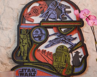 May include: A multi-layered wooden Star Wars themed wall art piece. The artwork is shaped like a Stormtrooper helmet and features various characters and vehicles from the Star Wars franchise, including Darth Vader, Luke Skywalker, and the Millennium Falcon. The piece is in shades of red, blue, green, and black.