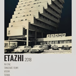 Op de afbeelding: Een zwart-witfoto van een groot, modern appartementencomplex met de tekst "ETAZHI 2018" en "МОЛЧАТ ДОМА" in het Russisch. Het gebouw heeft veel ramen en balkons. Er staan ​​verschillende auto's voor het gebouw geparkeerd.
