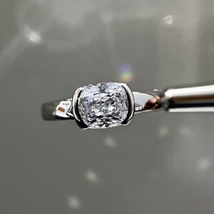 Peut inclure: Une bague en argent avec un grand diamant taille coussin transparent.
