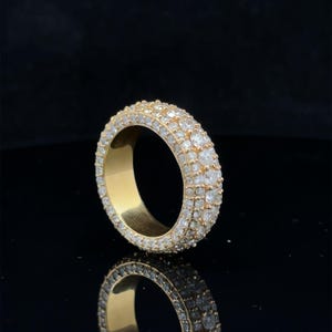 May include: A gold band ring with a thick band of pave set diamonds.