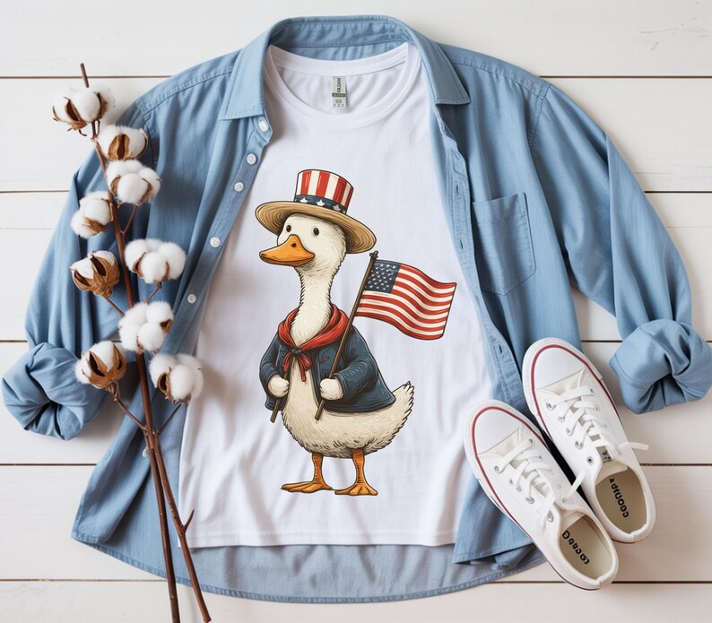 May include: White t-shirt featuring a cartoon duck wearing a patriotic hat and jacket, holding an American flag. The shirt is paired with a blue button-down shirt and white sneakers, creating a casual, all-American theme.