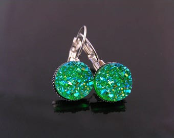 May include: A pair of leverback earrings with round, sparkling green druzy stones. The earrings have a silver-colored metal setting and leverback closure. The druzy stones have a textured, crystalline appearance, with flecks of blue and yellow.