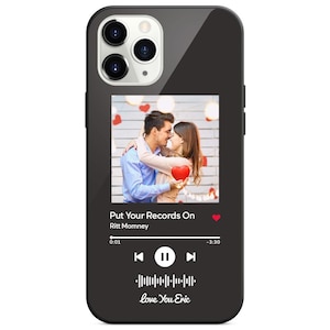 Peut inclure: Coque de téléphone noire avec une photo d'un couple s'embrassant, tenant un cœur rouge. Le design de la coque comprend une interface de lecteur de musique avec le texte "Put Your Records On" et "Love You Eric."