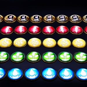 Puede incluir: Un conjunto de 50 fichas redondas de colores con varios símbolos, incluyendo una pluma, una llama, una planta y una gota de agua. Las fichas están dispuestas en cinco filas de diez, con cada fila presentando un símbolo diferente.