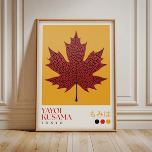May include: A framed art print showcasing a red maple leaf with black polka dots on a yellow backdrop. The print includes the text "YAYOI KUSAMA TOKYO" and Japanese characters. The artwork is presented in a wooden frame.