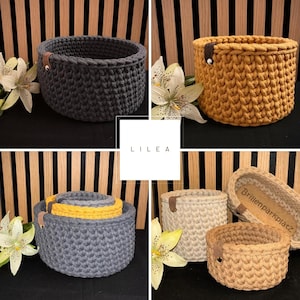 May include: A collection of round, crocheted storage baskets in dark gray, mustard yellow, and beige. Each basket features a small brown leather-like tab with a metal rivet. A central white square displays the text L I L E A and Brillenparkplatz.