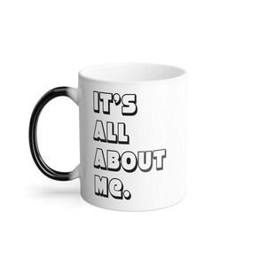 May include: White ceramic coffee mug with a black handle. The mug has black text that reads "IT'S ALL ABOUT ME."
