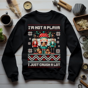 Op de afbeelding: Zwart sweatshirt met een kerstthema met een notenkraker met de tekst "I'm not a playa I just crush a lot".