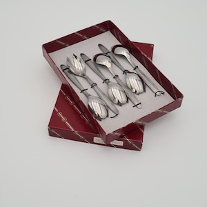 May include: A set of six silver-coloured spoons and forks, presented in a red box. The utensils have a tulip-shaped design on the spoon bowls and fork tines. The box is red with a decorative pattern.