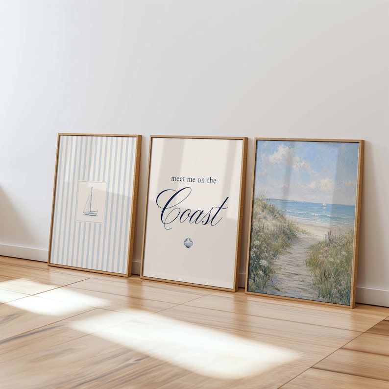 May include: Three framed coastal art prints. The first shows a sailboat on blue and white stripes. The second says "meet me on the Coast" with a seashell graphic. The third is a beach scene with a path to the sea.