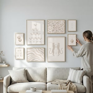 May include: A gallery wall arrangement of eight framed prints in light wood frames. The prints feature a champagne tower, a leopard print pattern, a heart necklace, two leopards, wavy lines, the text HOW LUCKY ARE WE, and two billiard balls.