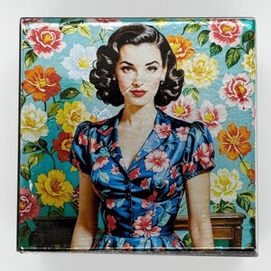 May include: A woman in a blue floral dress stands in front of a floral wallpaper. The wallpaper is a light blue with pink, yellow, and white flowers. The woman has dark hair and red lipstick.