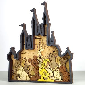 May include: A wooden Disney castle-shaped decoration featuring various Disney characters. The castle is dark brown with a light brown interior, and the characters are in various colours. Characters include Mickey Mouse, Winnie the Pooh, and Simba.