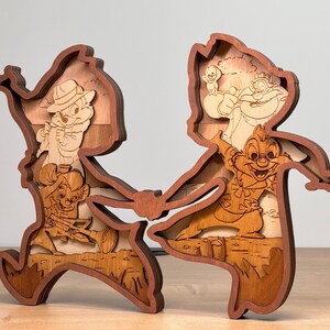 May include: A wooden layered art piece featuring Chip and Dale, the Disney chipmunks. The artwork is made of various shades of brown wood, with the characters and background details intricately carved and layered to create a 3D effect. The chipmunks are depicted in their classic poses.